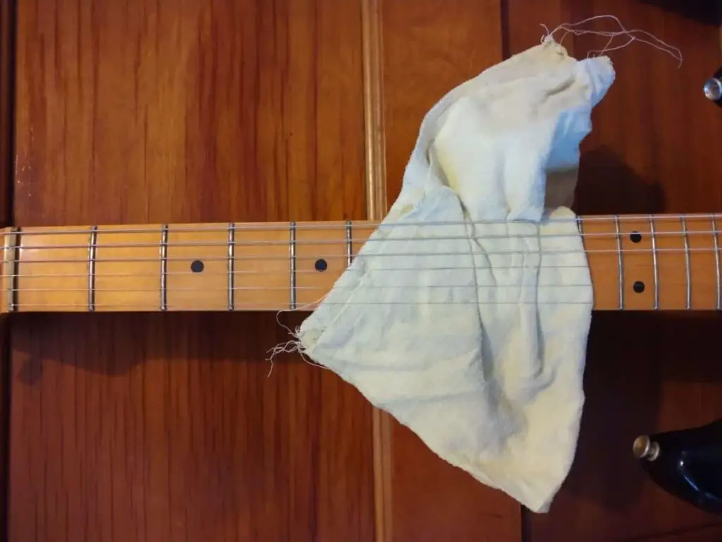 guitar fretboard with cloth under strings